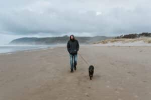 man walking dog on beach - ethical travel - baboo