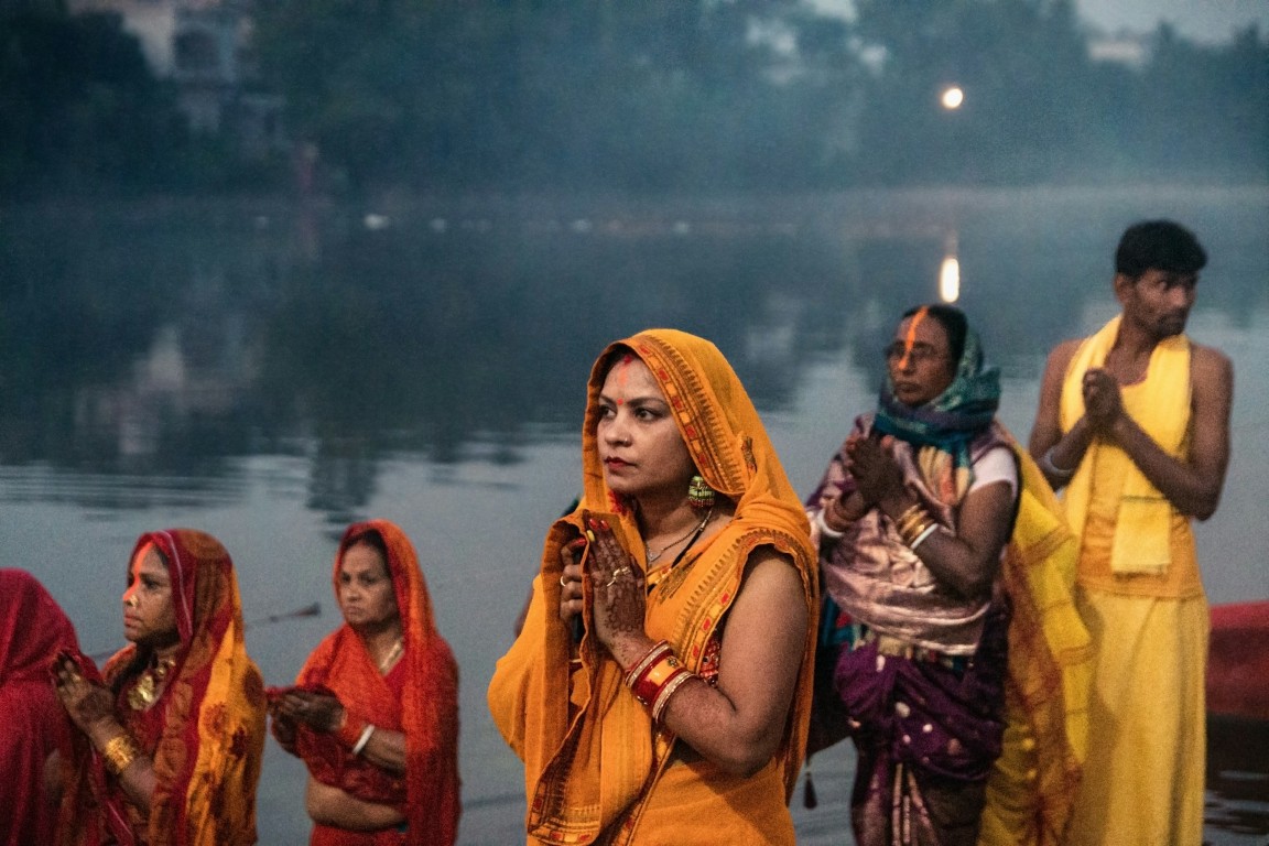 people in cultural clothing praying beside the river in bengal india