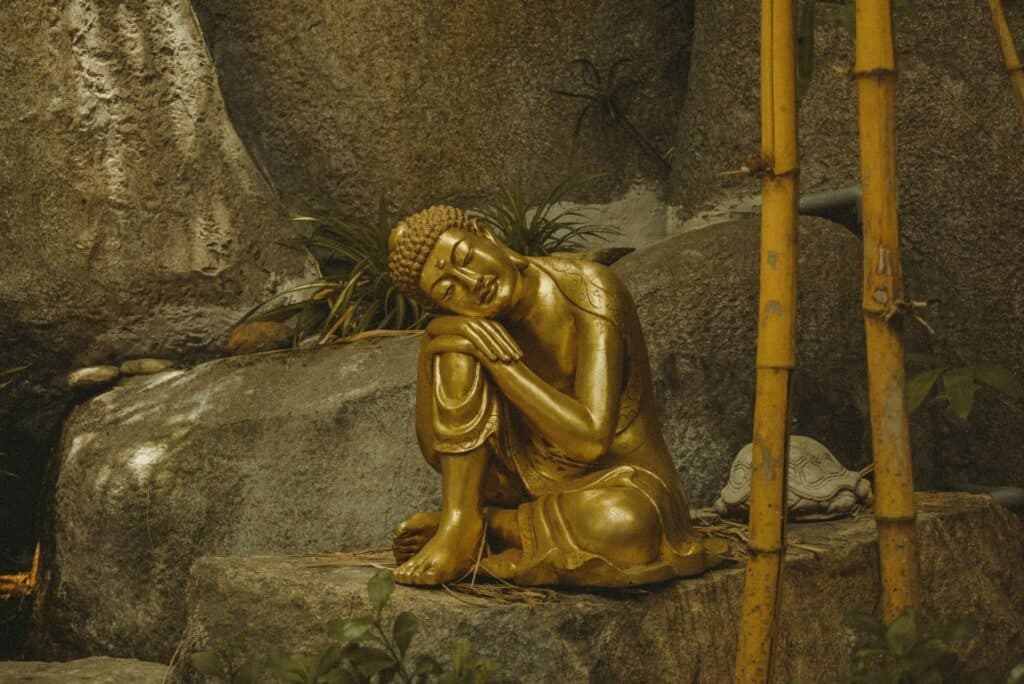small golden buddha statue sitting on a rock